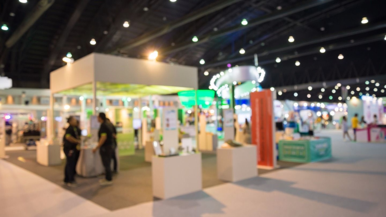 ticari bir fuarda firmaların standlarında çalışmalarını inceleyen insanlar