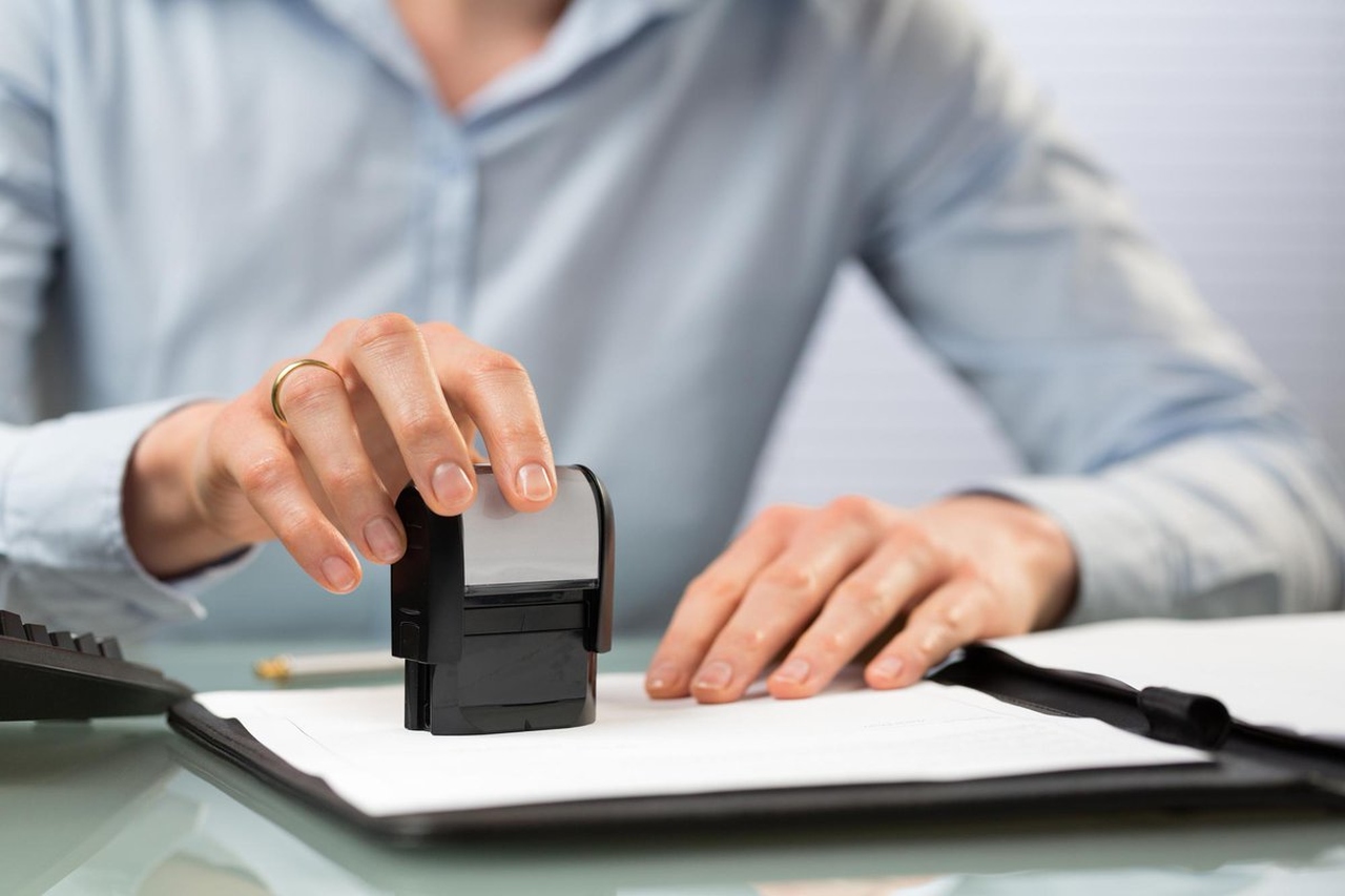 Bir evrak üzerine kendinden mürekkepli kaşe basan adam