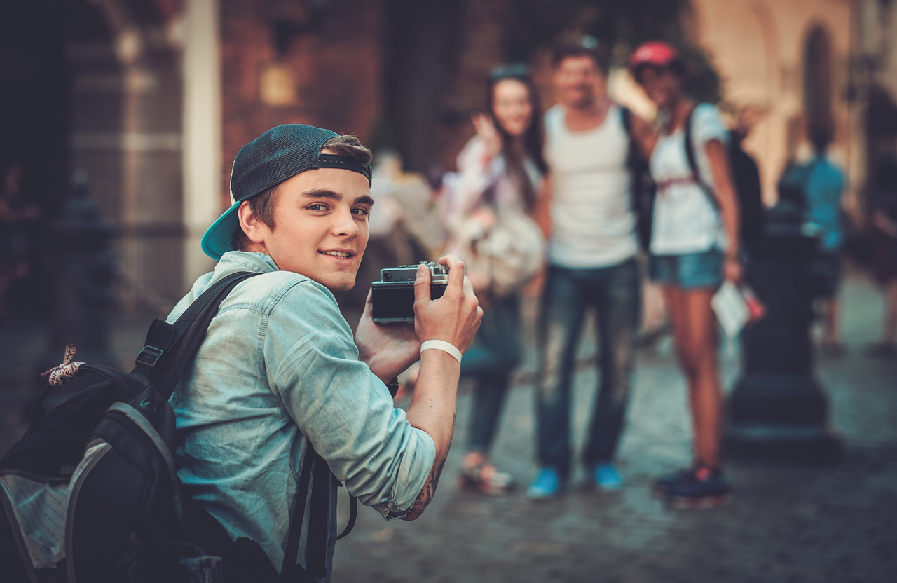 Poz veren 3 kişinin fotoğrafını çekerken arkasını dönerek poz veren fotoğrafçı