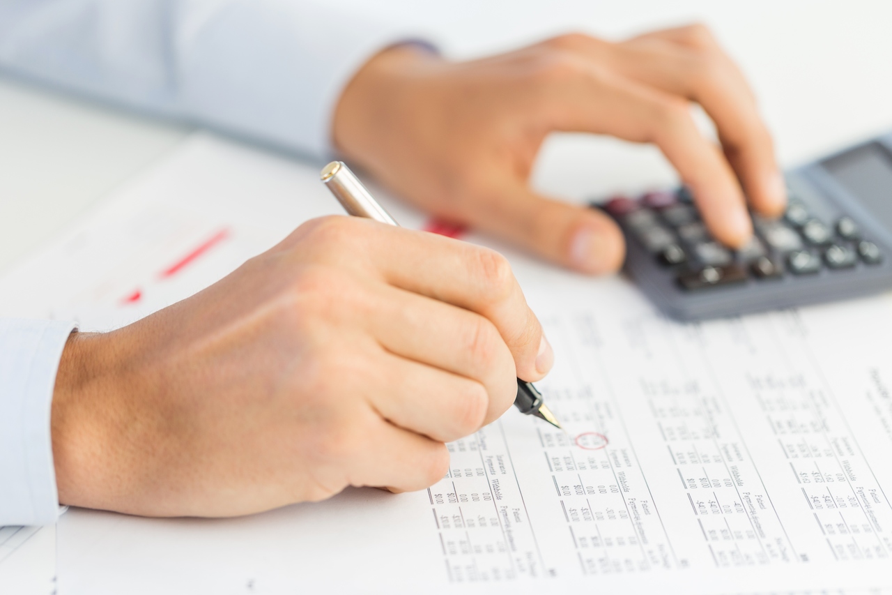 hesap makinesi ile çizelge üzerinde hesap yapan adam eli