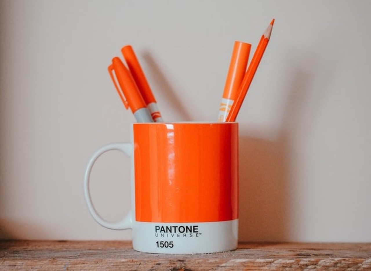 Turuncu renkte pantone yazan bardağa koyulmuş turuncu kalemler