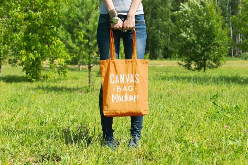 Elinde üzeri yazılı sarı bez çanta tutan bir kadın görseli