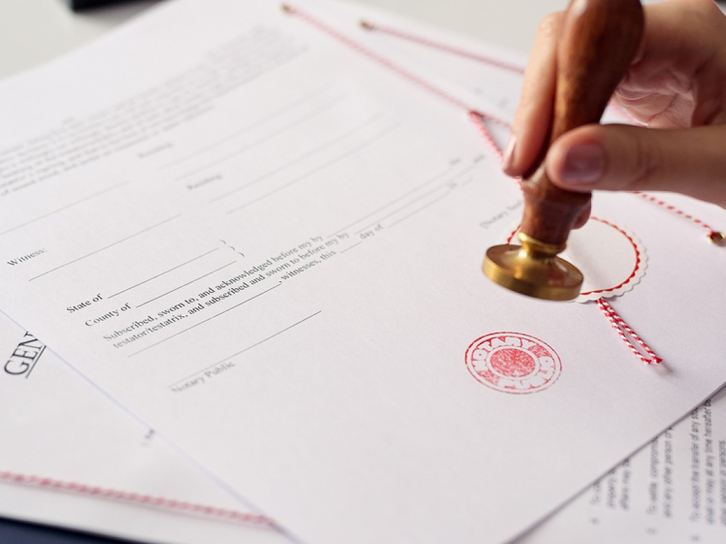 beyaz bir sertifikaya kırmızı damga basan kadın eli